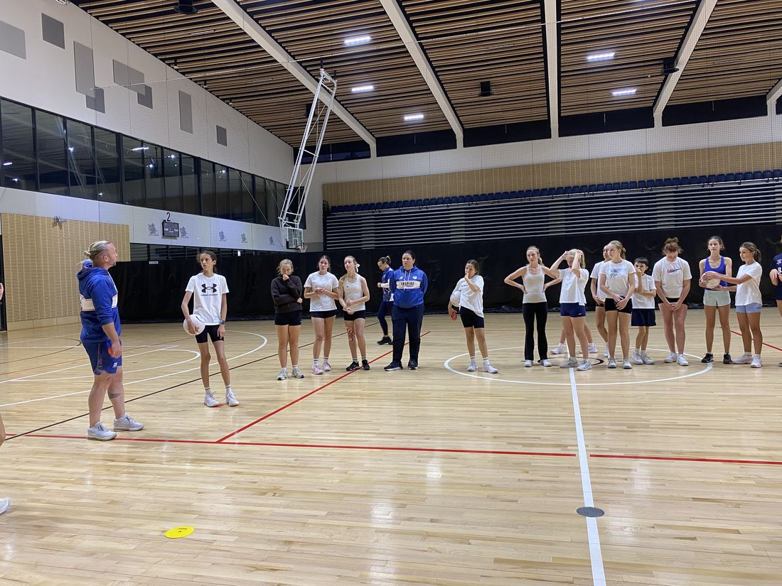 Athletes listening to an Inspire coach at an indoor court
